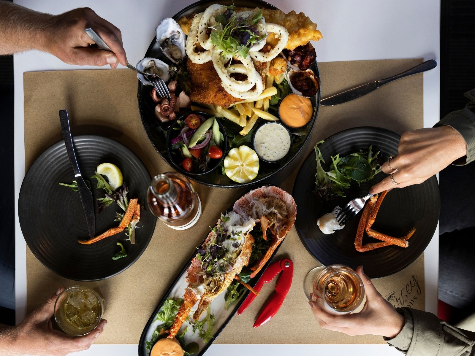 Diners sharing Tasmanian rock lobster and a seafood platter in Stanley, Tasmania.