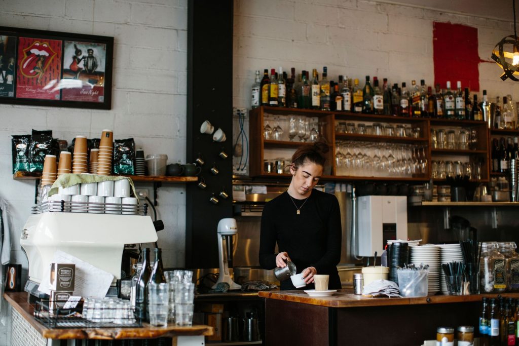 A barista pouring milk into a coffee at the counter of Laneway Café in Devonport.