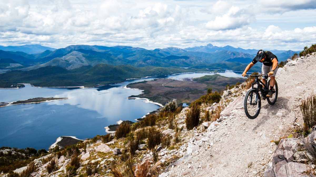 Mountain biker descending a rocky Mount Owen trail above Lake Burbury near Queenstown, Tasmania.